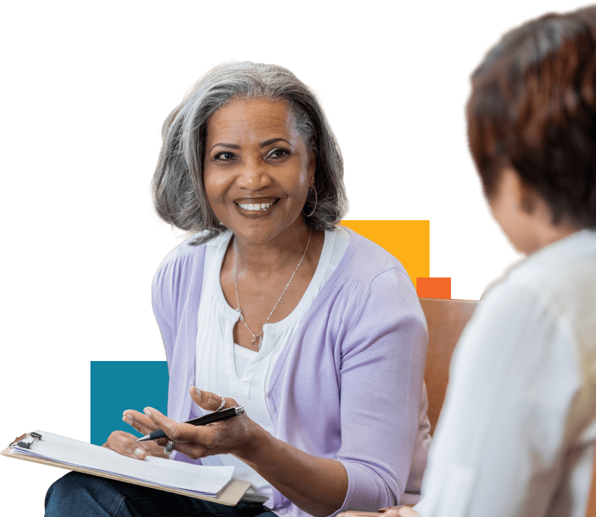 Seasoned Black school district leader holding a clipboard with student data in a discussion with another woman.