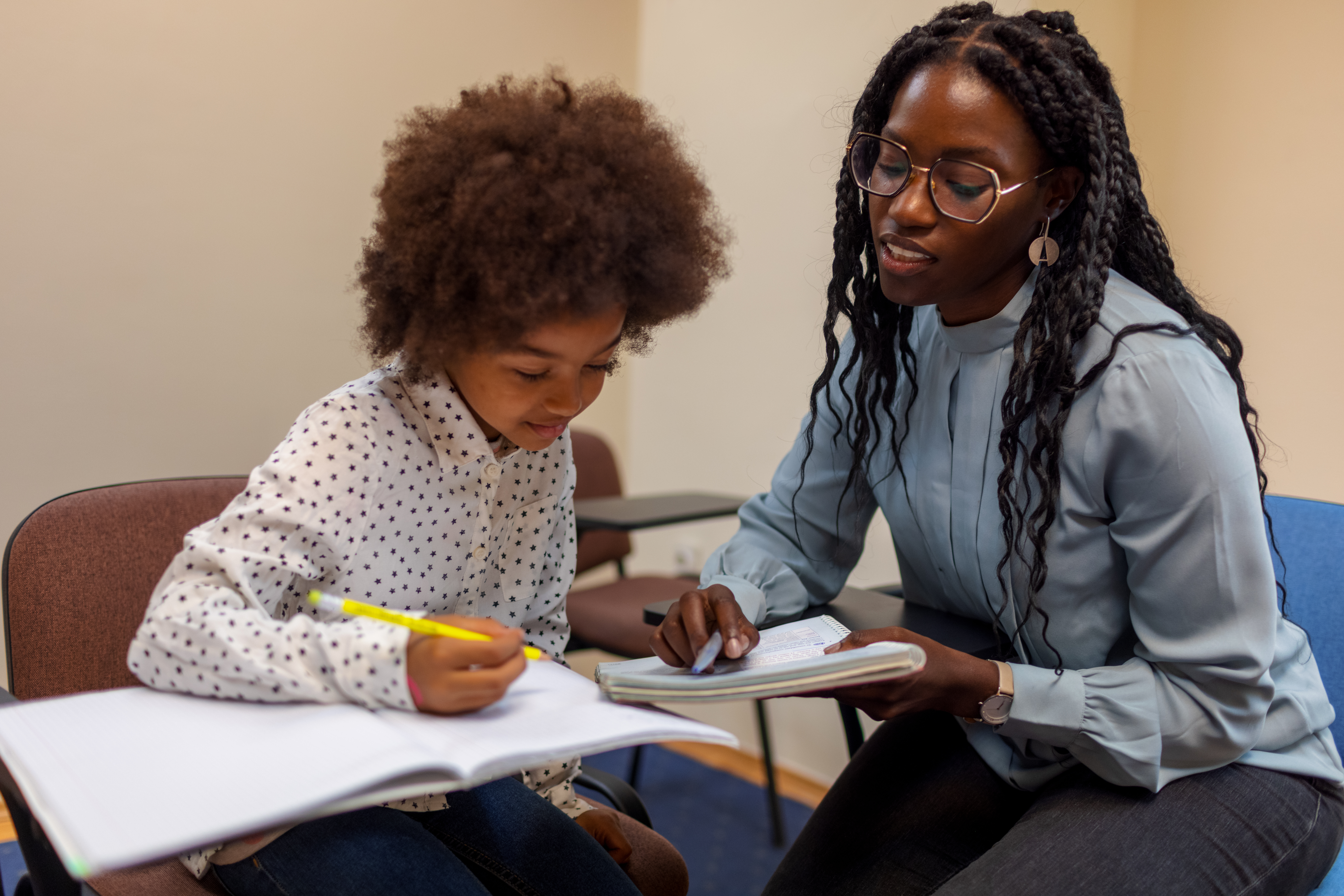 Black teacher helps her elementary student with math.