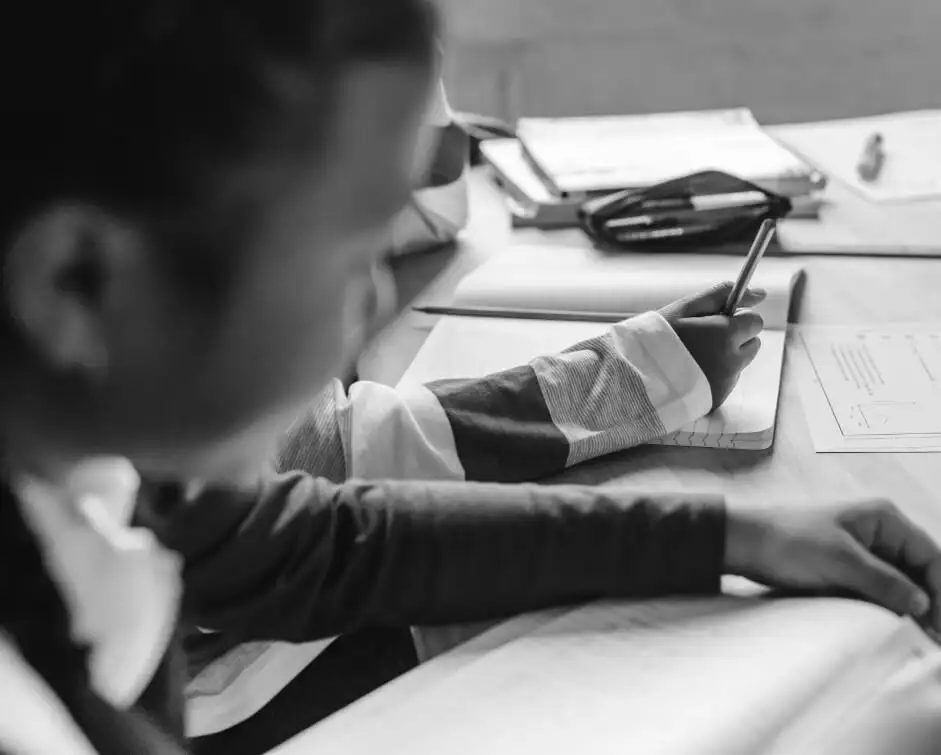Black and white photo of elementary school students working collaboratively and writing in their composition notebooks.