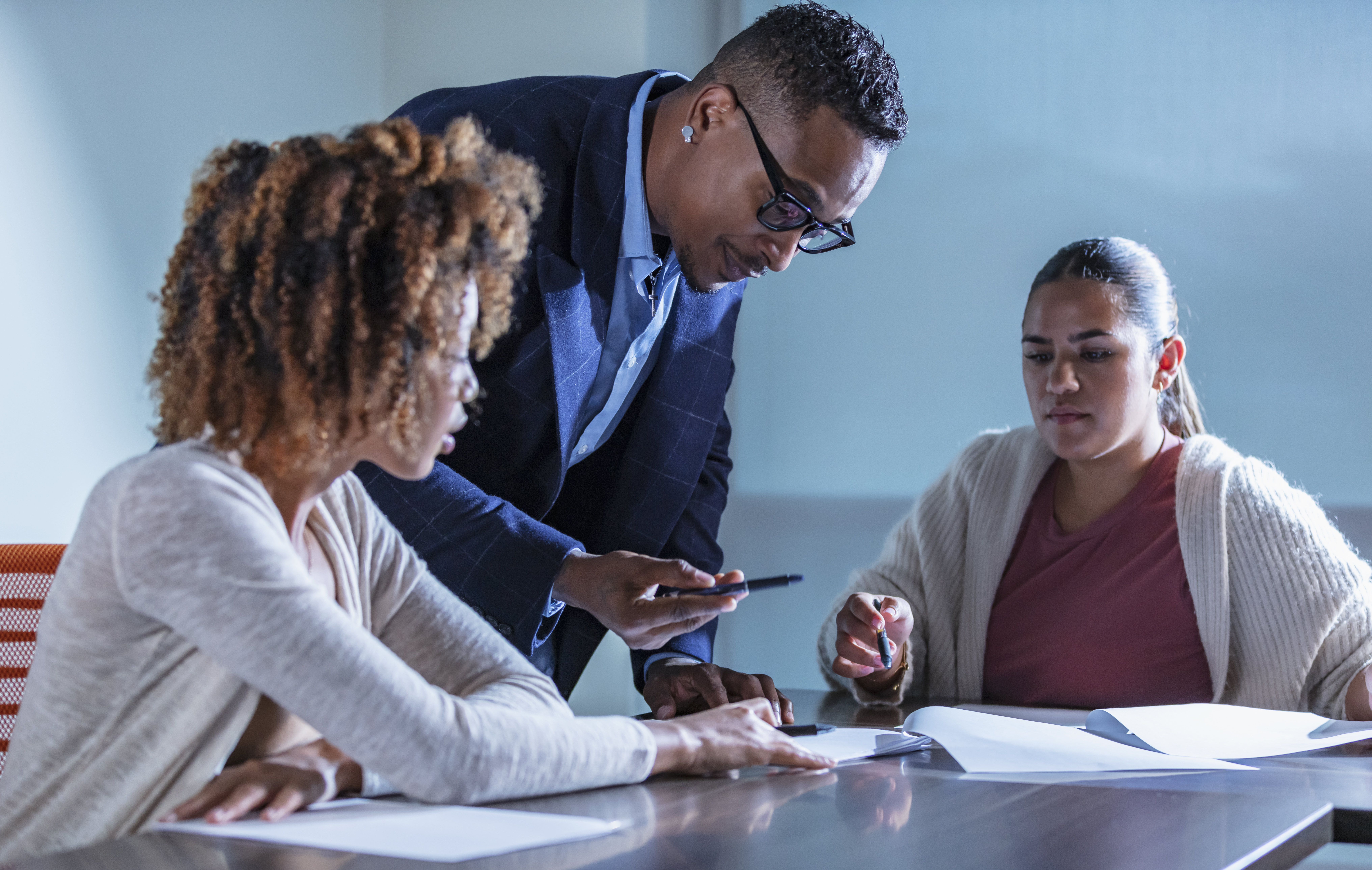 A multiracial group of three district leaders in a meeting, reviewing data on K-8 math core and supplemental materials.