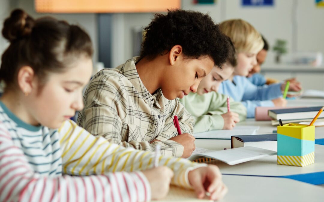 Mix of diverse students writing at desk.