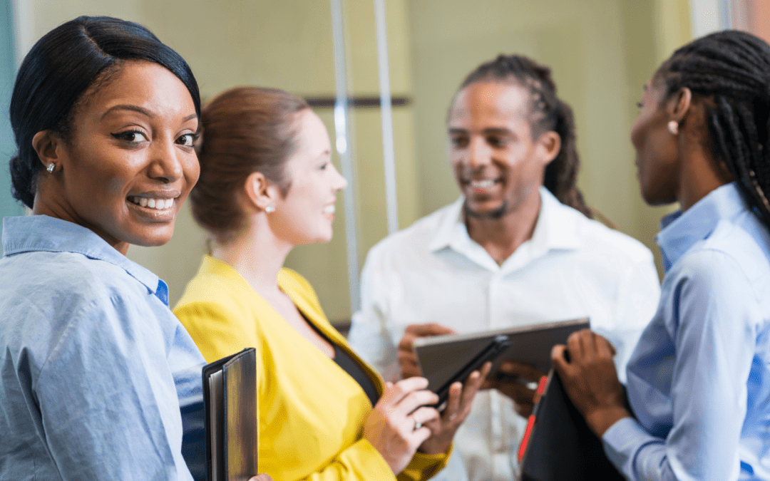 A group of four diverse school leaders discussing curriculum, smiling.