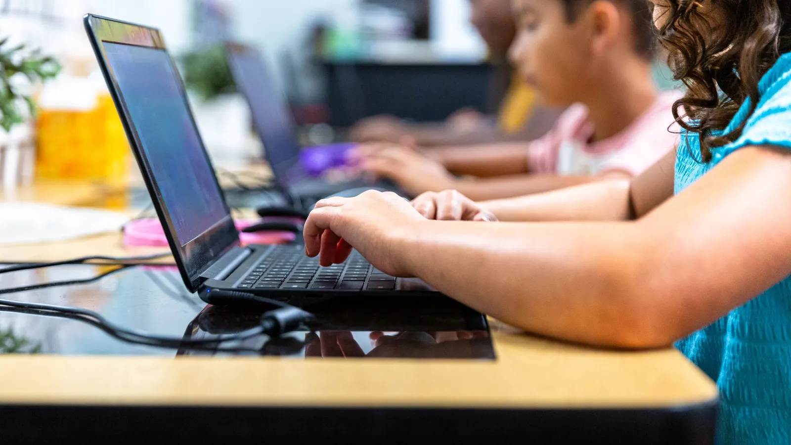 A row of elementary school students working on laptop computers.
